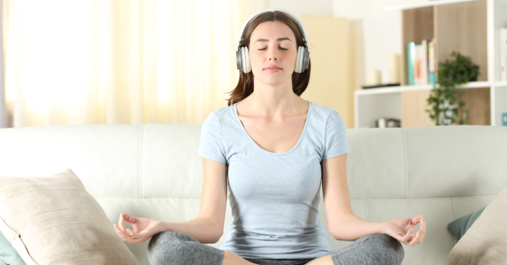 Person meditating with headphones - Dreamteampromos.com